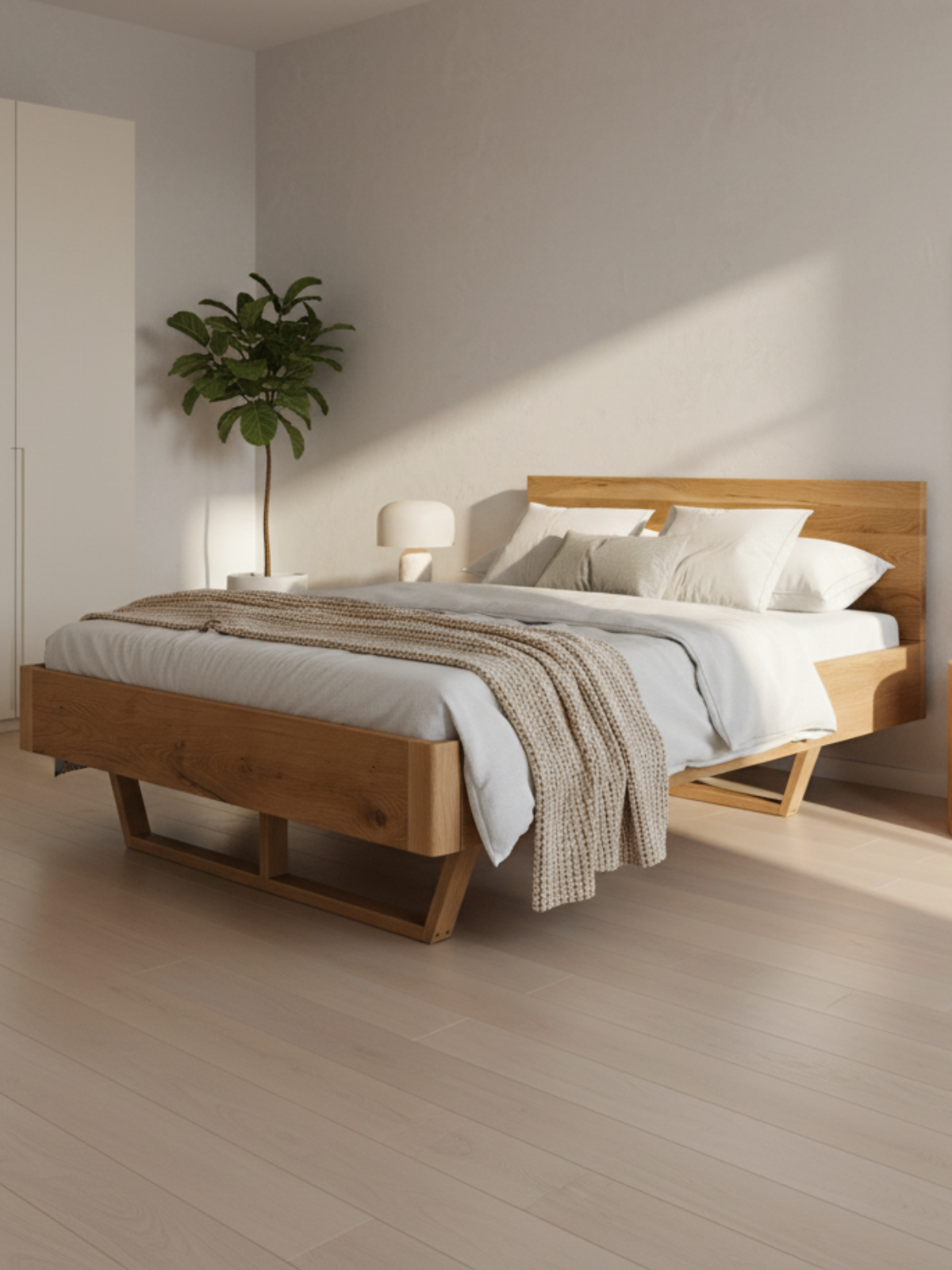 Massivholzbett aus Eiche in einem hellen, minimalistischen Schlafzimmer mit Zimmerpflanze und Leuchte